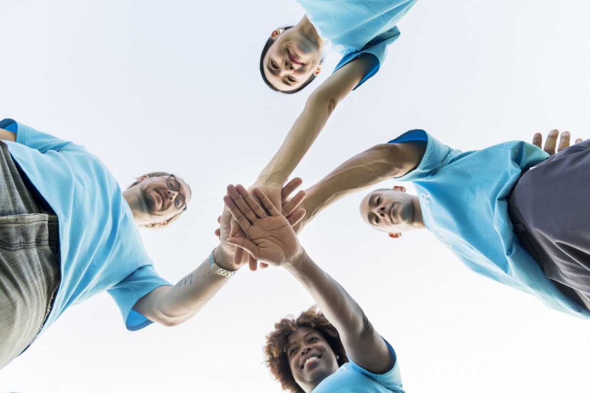 Community volunteers bringing their hands together in a show of teamwork